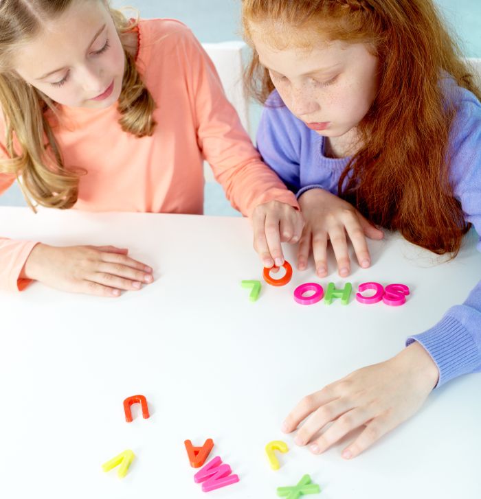 Image of two school children with the letters of the alphabet working together at a classroom center.